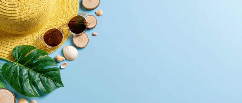 Summer beach accessories arranged in flat lay on blue background with copyspace