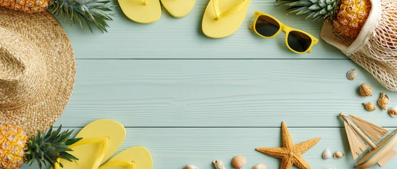 Summer beach accessories arranged on a pale mint wooden table with copyspace