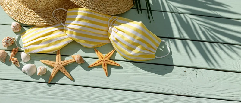Yellow and white striped face masks with starfish and seashells on a wooden deck