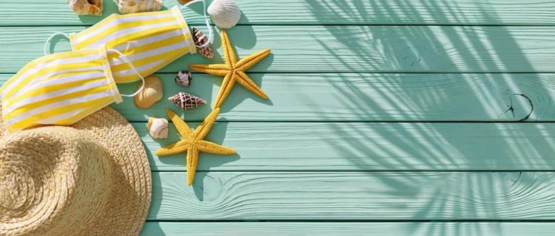 Yellow and white striped face masks with starfish and seashells on a turquoise wooden deck, flat lay top view