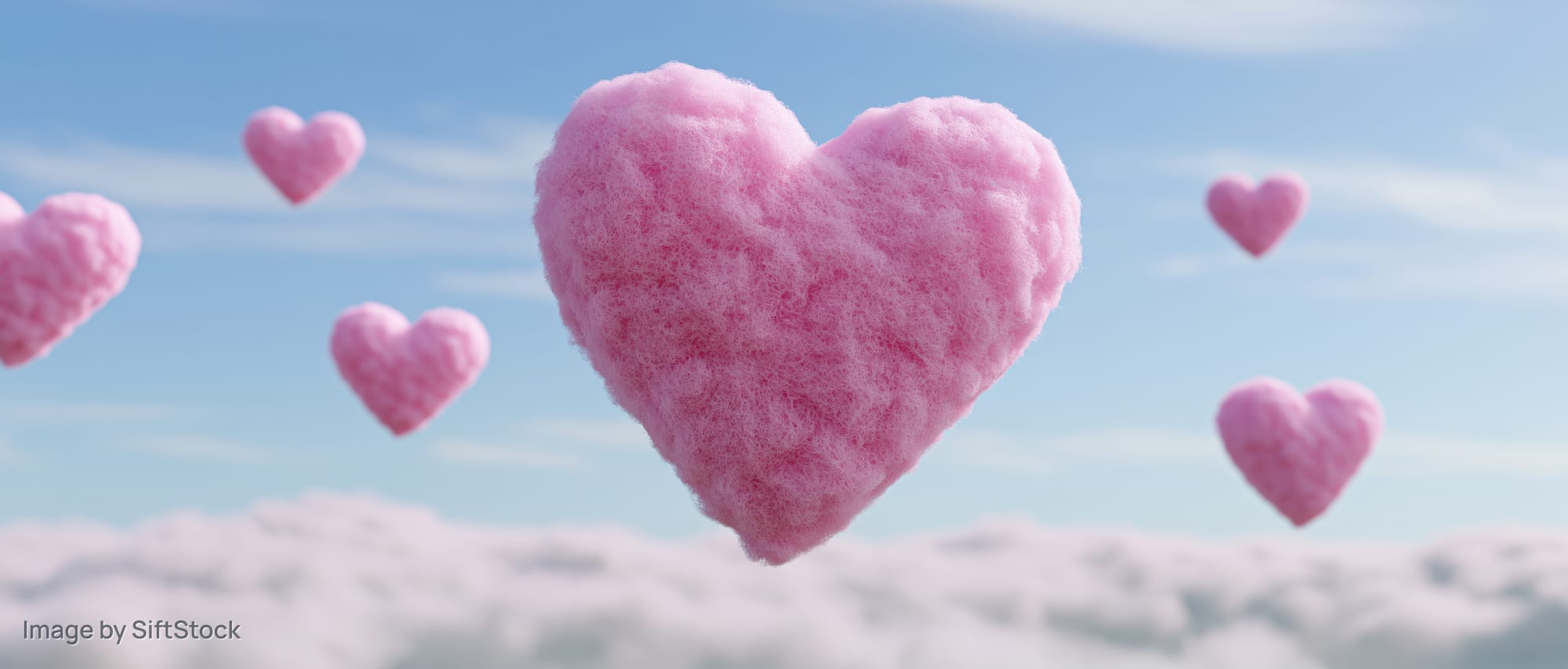 Fluffy pink heart-shaped balloons floating above clouds in a blue sky