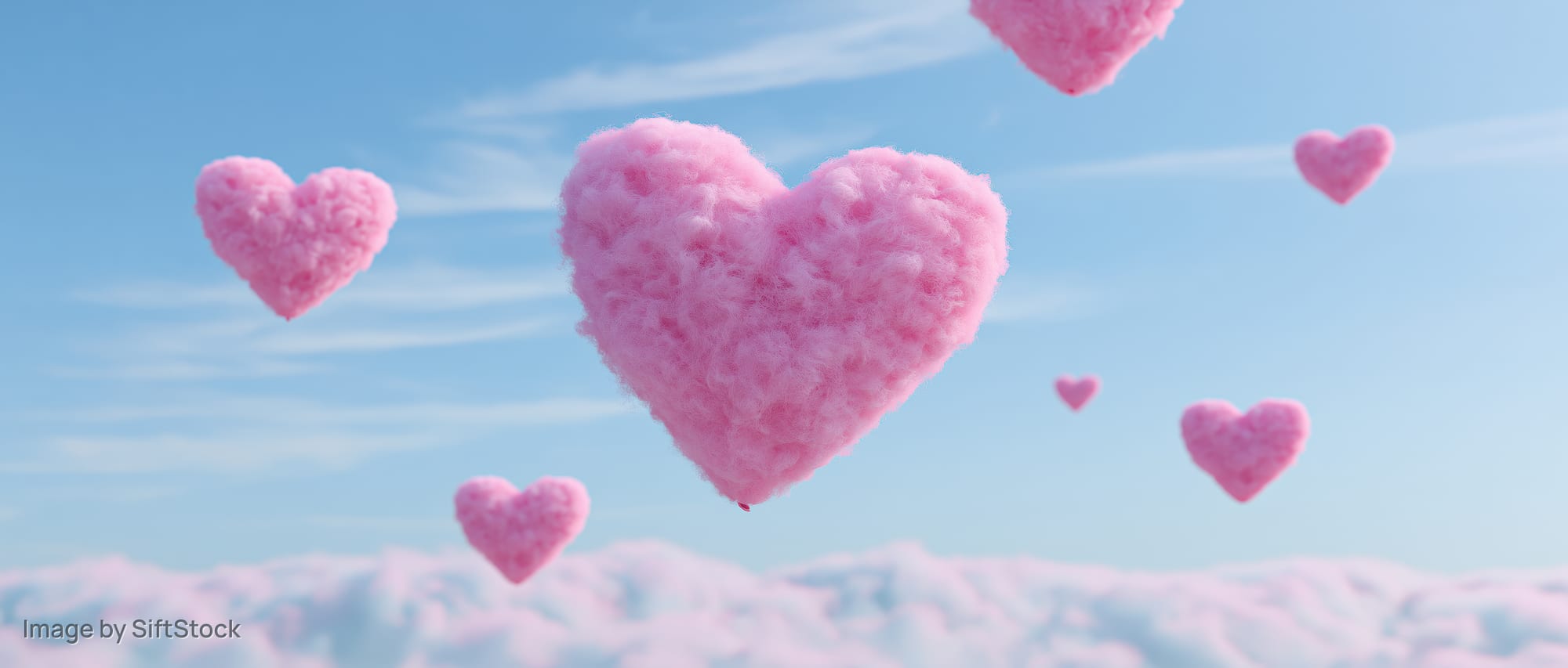 Fluffy pink heart-shaped balloons floating above clouds in a clear blue sky