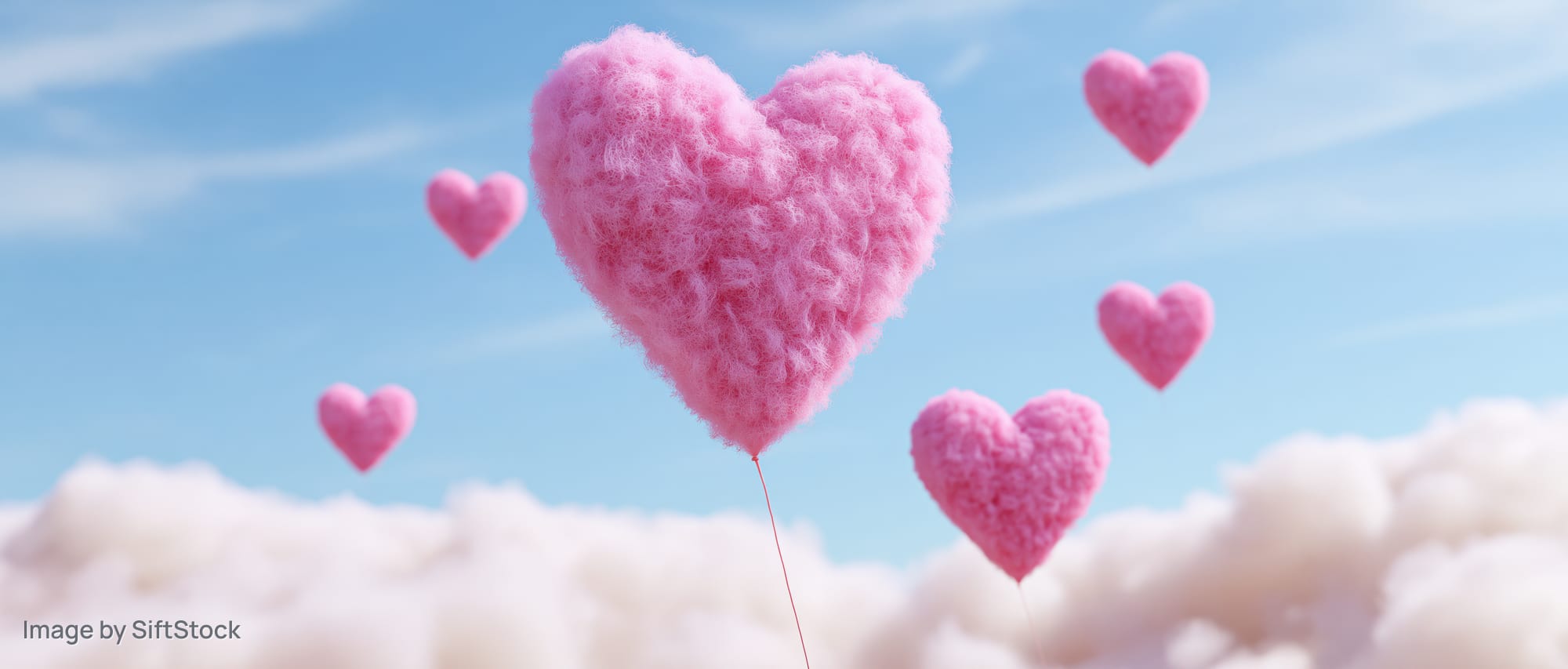 Fluffy pink heart-shaped balloons floating above clouds in a blue sky