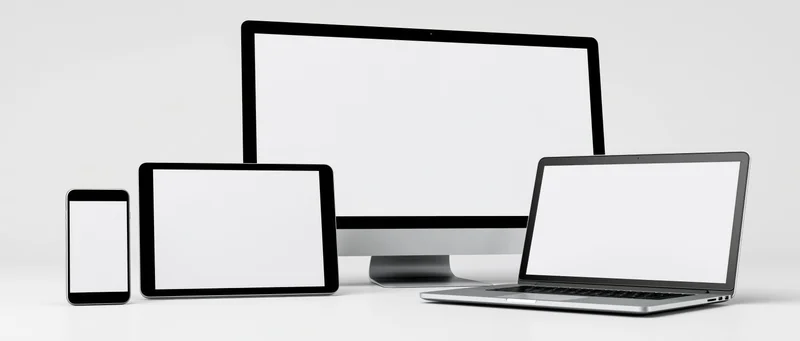 Four blank-screen digital devices arranged in a row on a white surface