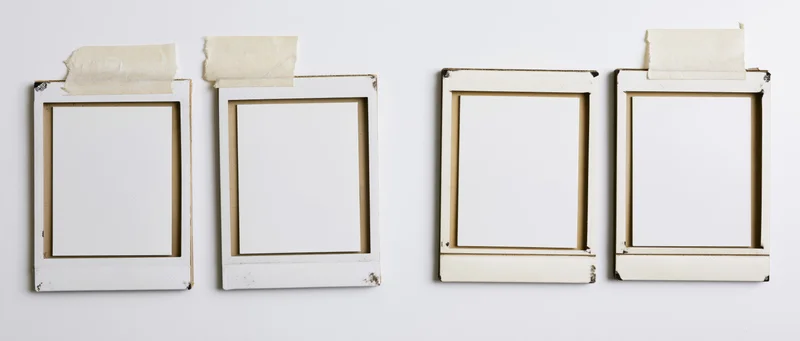 Four blank instant film photo frames arranged in a row on a white wall