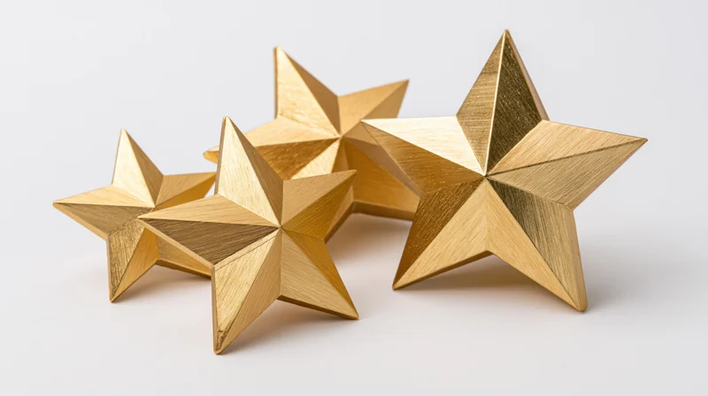Four metallic gold star decorations arranged in a loose cluster on a white surface