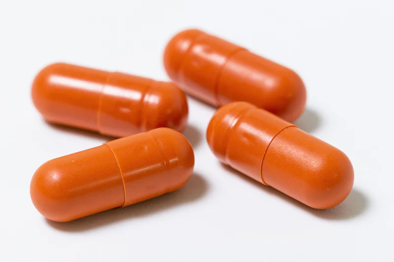 Four orange gelatin capsules scattered on a white surface