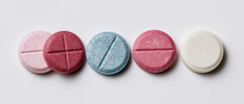 Five round pharmaceutical tablets arranged in a row on a white surface