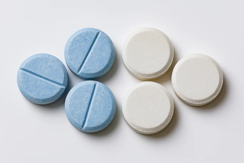 Blue and white round scored tablets arranged in two groups on white background