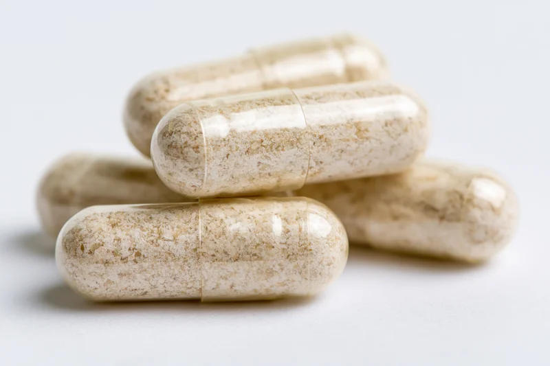 Translucent gelatin capsules filled with fine powder stacked on white surface