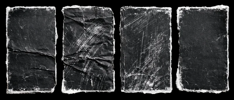 Four worn black paper rectangles arranged side by side on black background