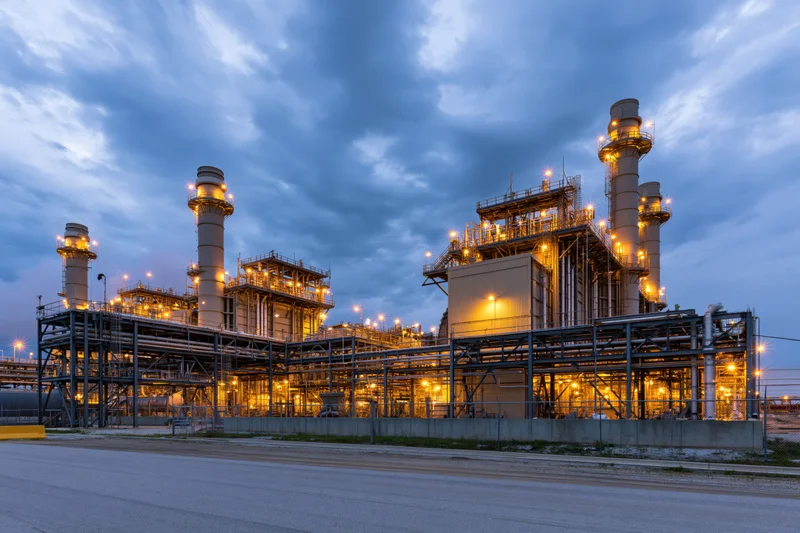 Gas turbine power plant illuminated at twilight with glowing structures and metal framework