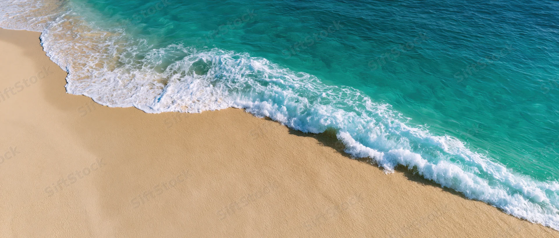 Gentle ocean wave washing over clean sandy beach from above