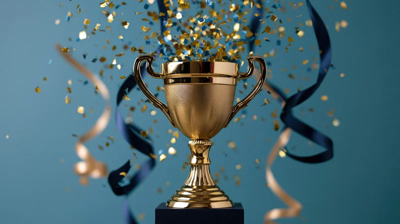 Golden trophy on dark pedestal with confetti and ribbons swirling around it