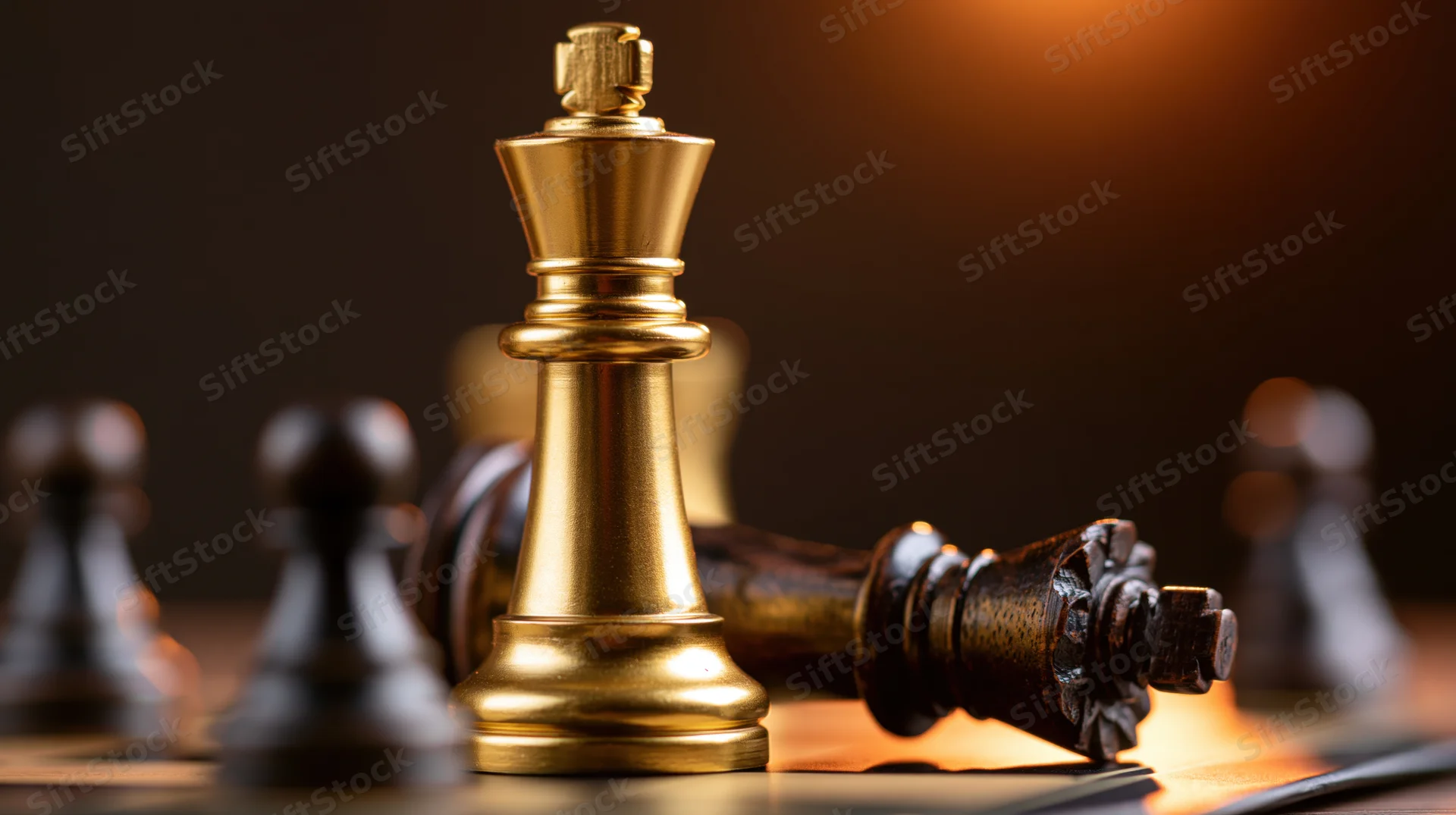 Gold chess king standing upright beside a fallen dark king on a chessboard under warm spotlight