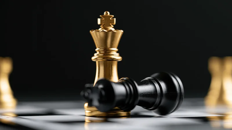 Gold chess king standing upright over a fallen black king on a chessboard