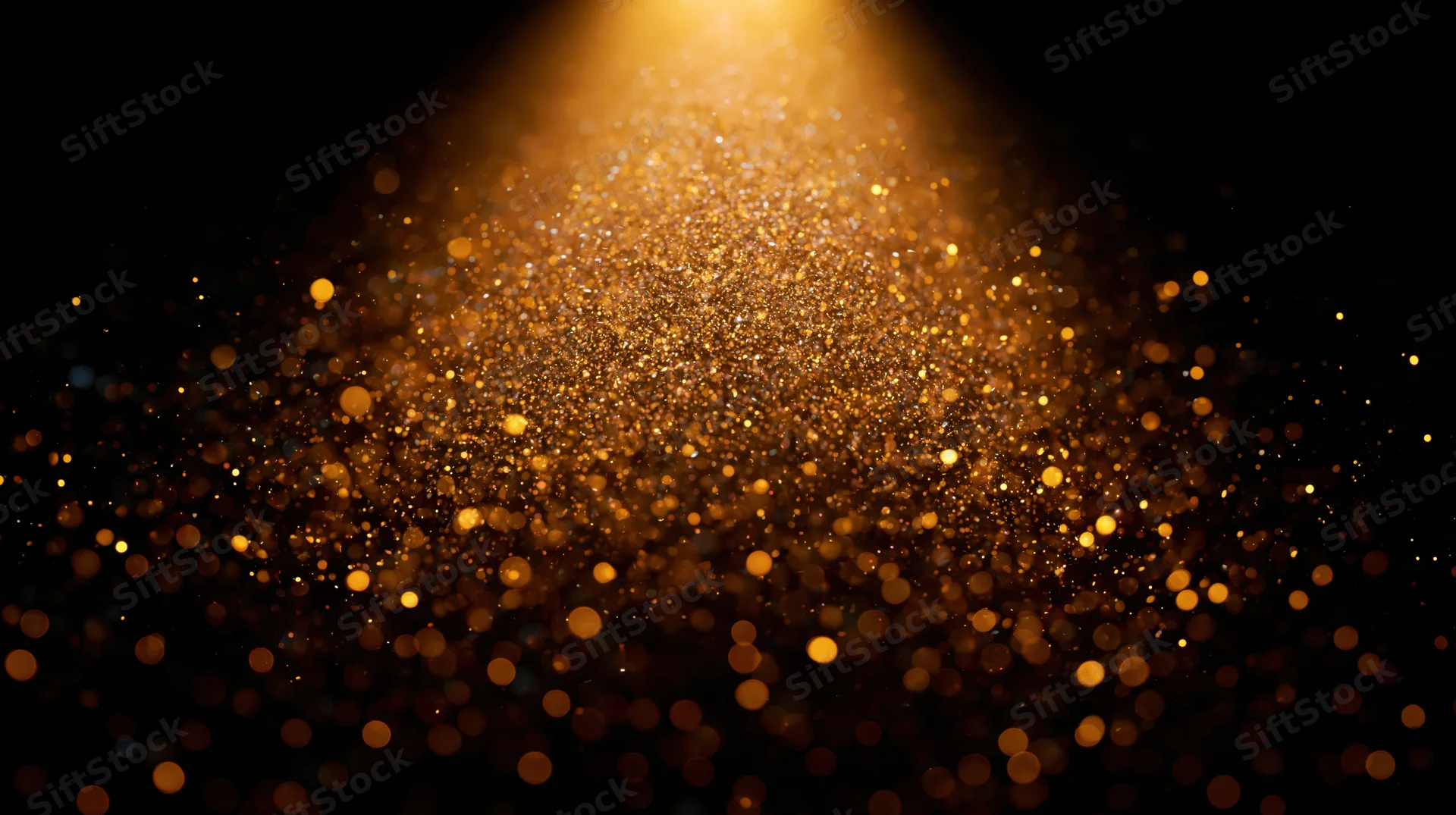 Golden dust particles floating in a beam of light against a dark background