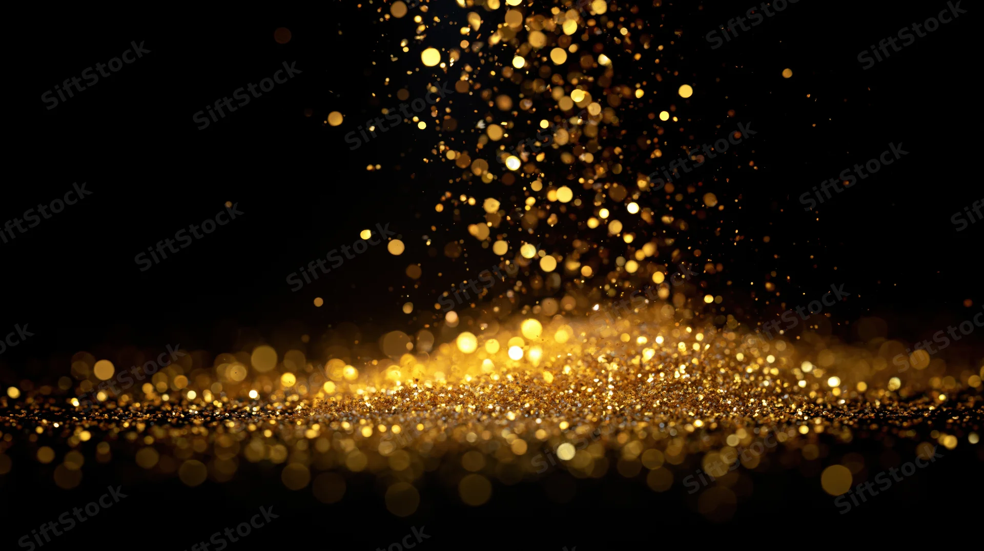 Golden glitter particles floating and falling against a dark background with bokeh lights and soft focus