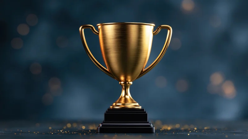 Golden trophy cup on black base centered on dark surface with bokeh lights