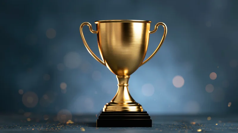 Golden trophy cup centered on dark surface with bokeh background