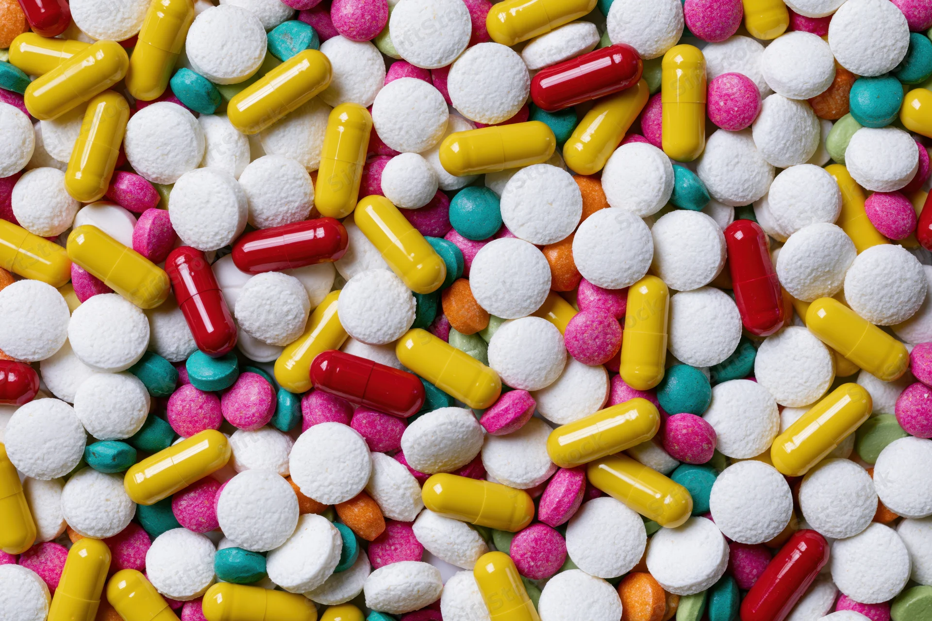 Assorted pharmaceutical pills tablets and capsules in a dense flat lay pattern