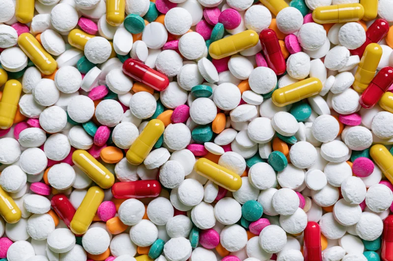 Assorted pharmaceutical pills tablets and capsules scattered in a heap viewed from above