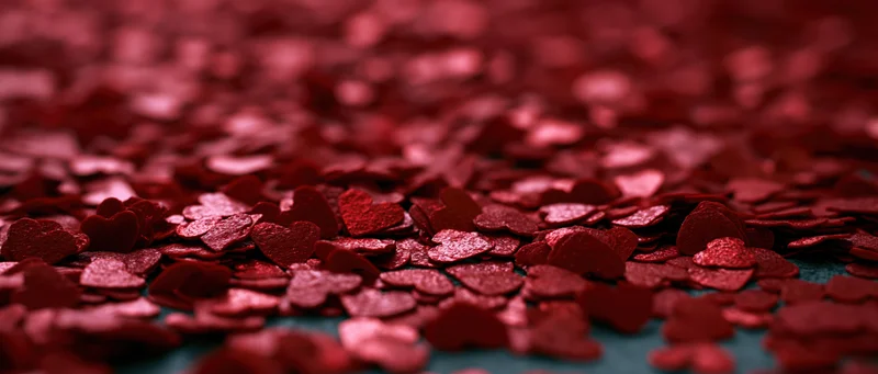 Red heart-shaped confetti scattered across a surface in shallow focus