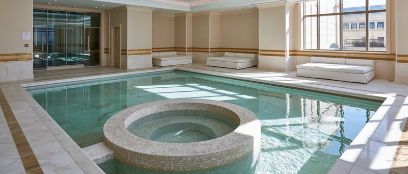 Indoor spa pool area with circular jacuzzi and tiled benches by large windows