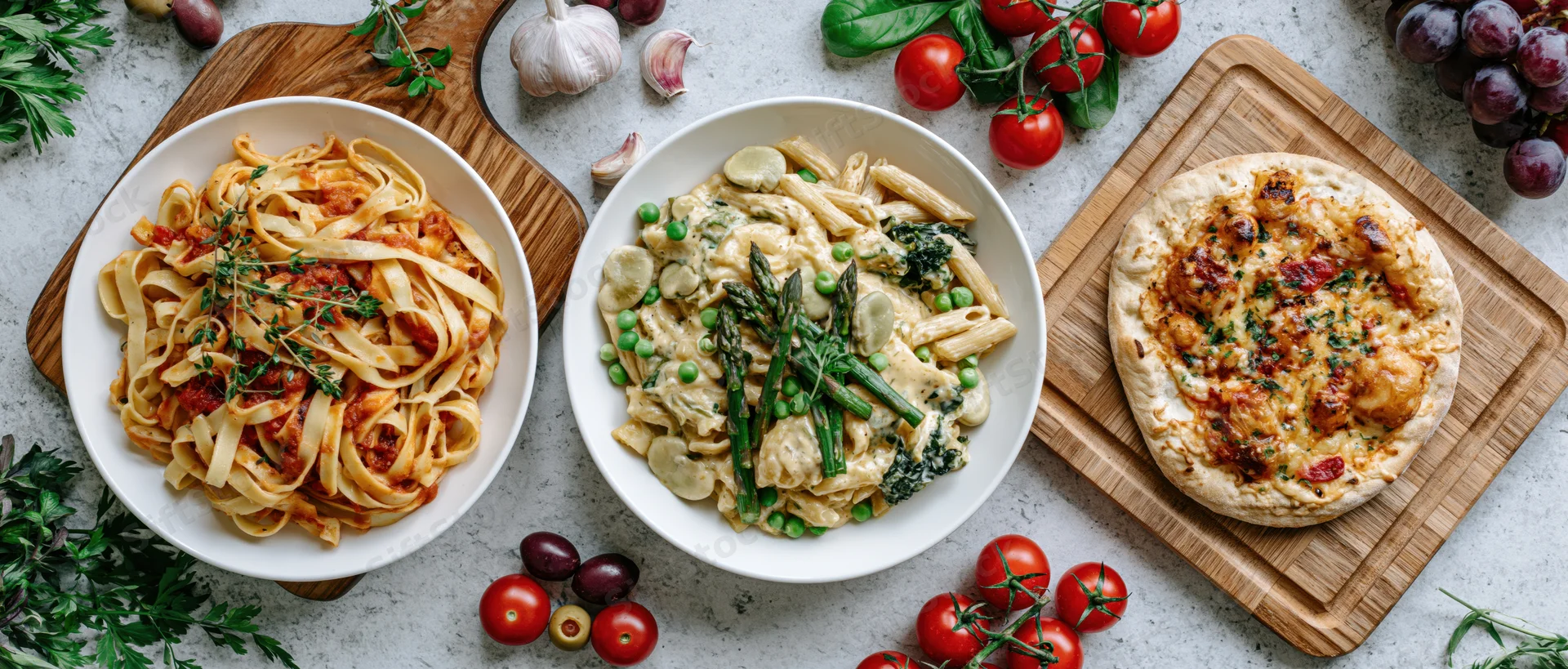 Italian food spread with pasta dishes and focaccia on wooden boards and concrete surface