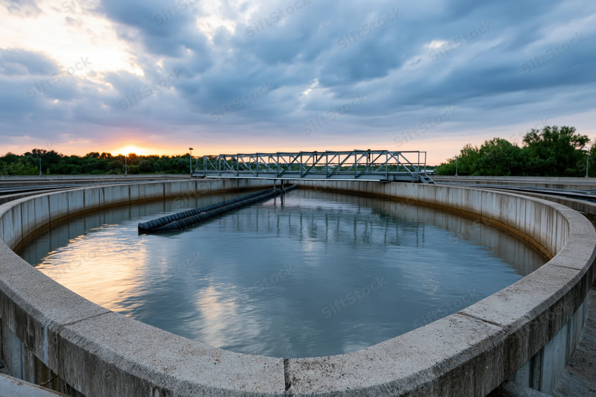 Circular clarifier tank at a wastewater treatment plant during sunset