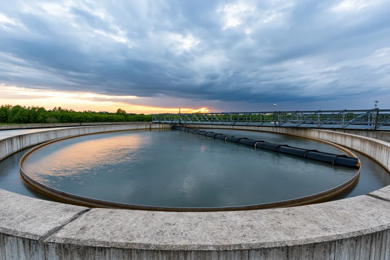Circular clarifier tank in a municipal wastewater treatment facility at sunset