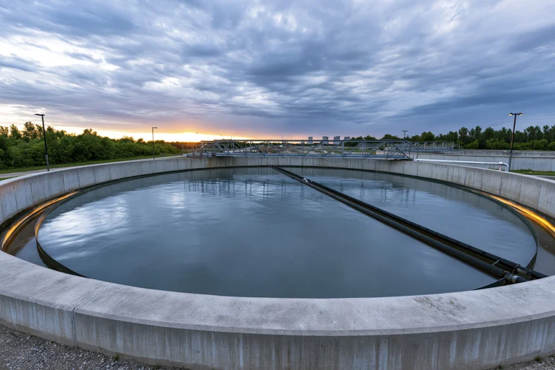 Circular wastewater clarifier tank at municipal treatment facility during sunset