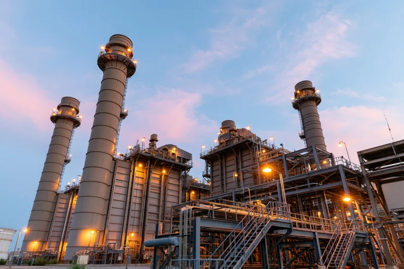 Large gas turbine power plant with tall exhaust stacks at dusk
