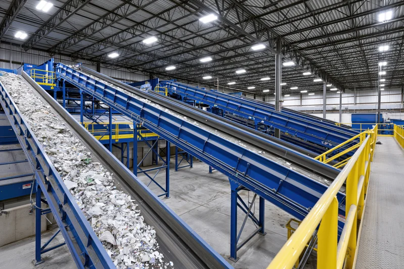 Conveyor belts transporting shredded waste materials through an industrial recycling facility interior