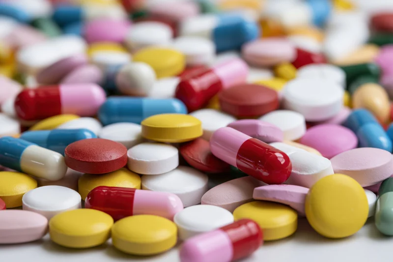 Assorted pharmaceutical pills and capsules piled together on a white surface