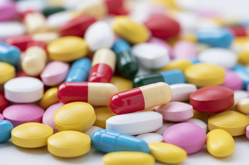 Assorted pharmaceutical pills and capsules scattered on a white surface