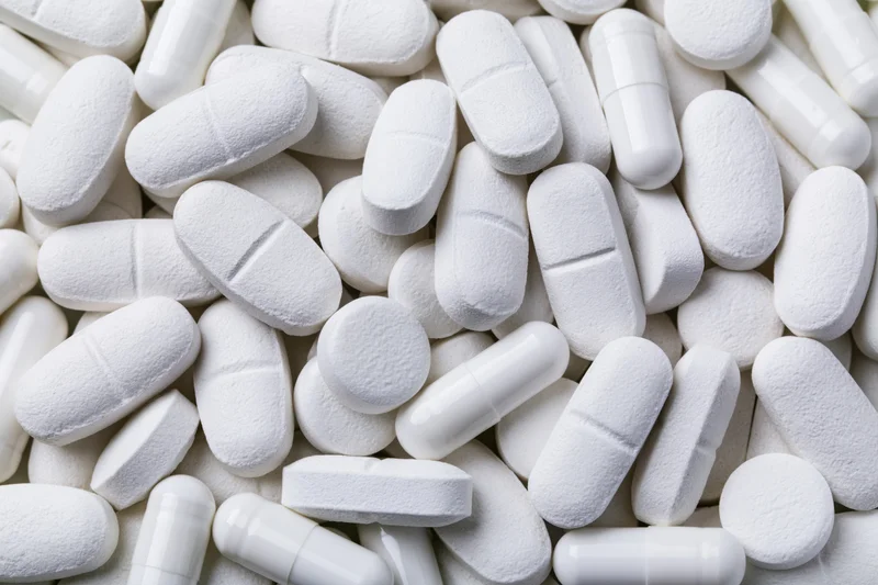 Close-up of assorted white pharmaceutical tablets and capsules piled together
