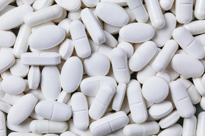 Close-up of assorted white pharmaceutical tablets and capsules piled together
