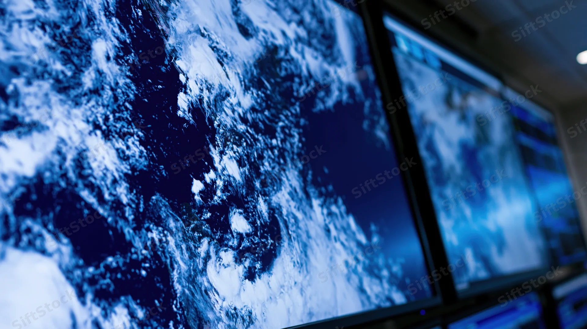 Large wall-mounted display screens showing satellite weather imagery in an operations control room
