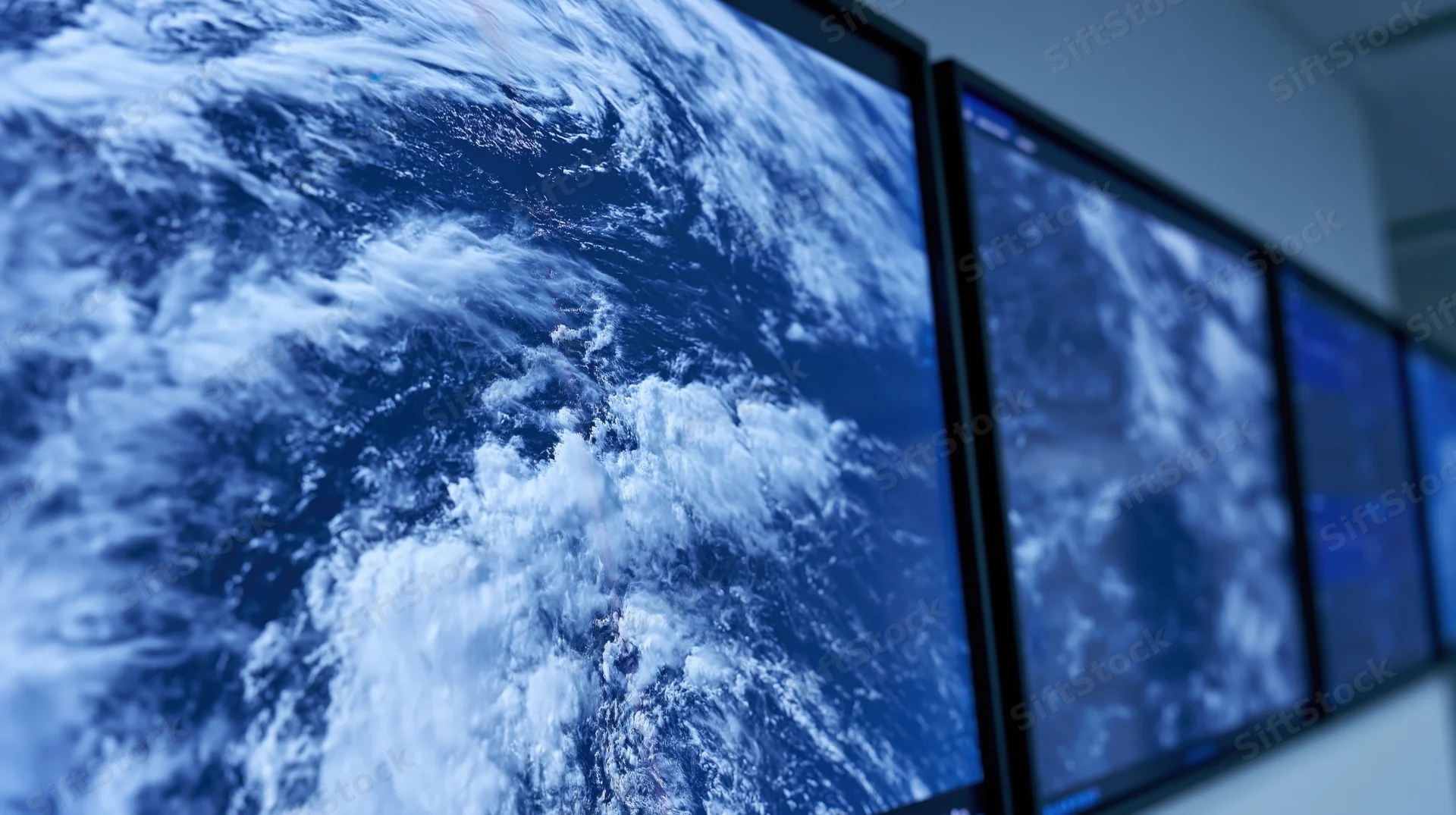 Wall-mounted display screens showing satellite view of earth's ocean waves in an operations control room