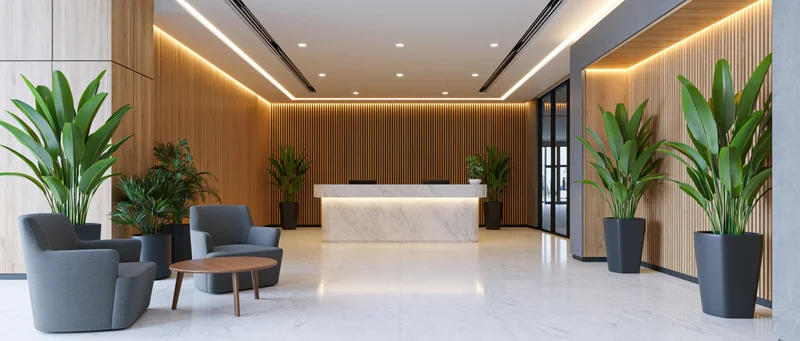 Modern hotel lobby with marble reception desk and potted plants arranged around seating area