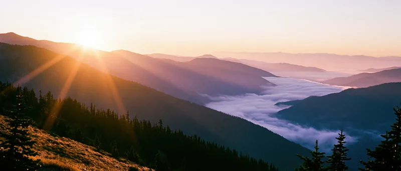 Mountain ridge at sunset with layered ridgelines receding into misty valley