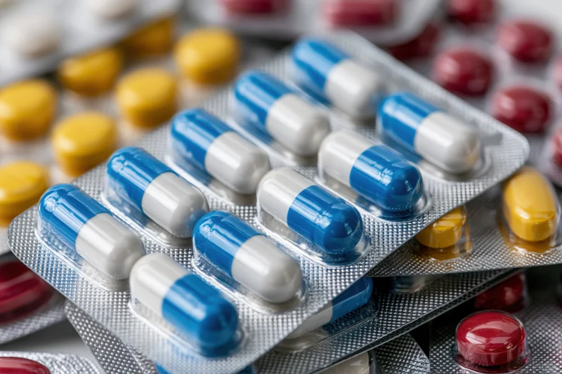 Multiple blister packs of assorted pharmaceutical pills and capsules in close-up view