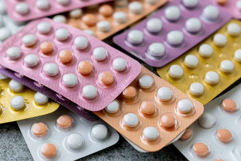 Multiple blister packs of oral contraceptive pills layered on a textured surface