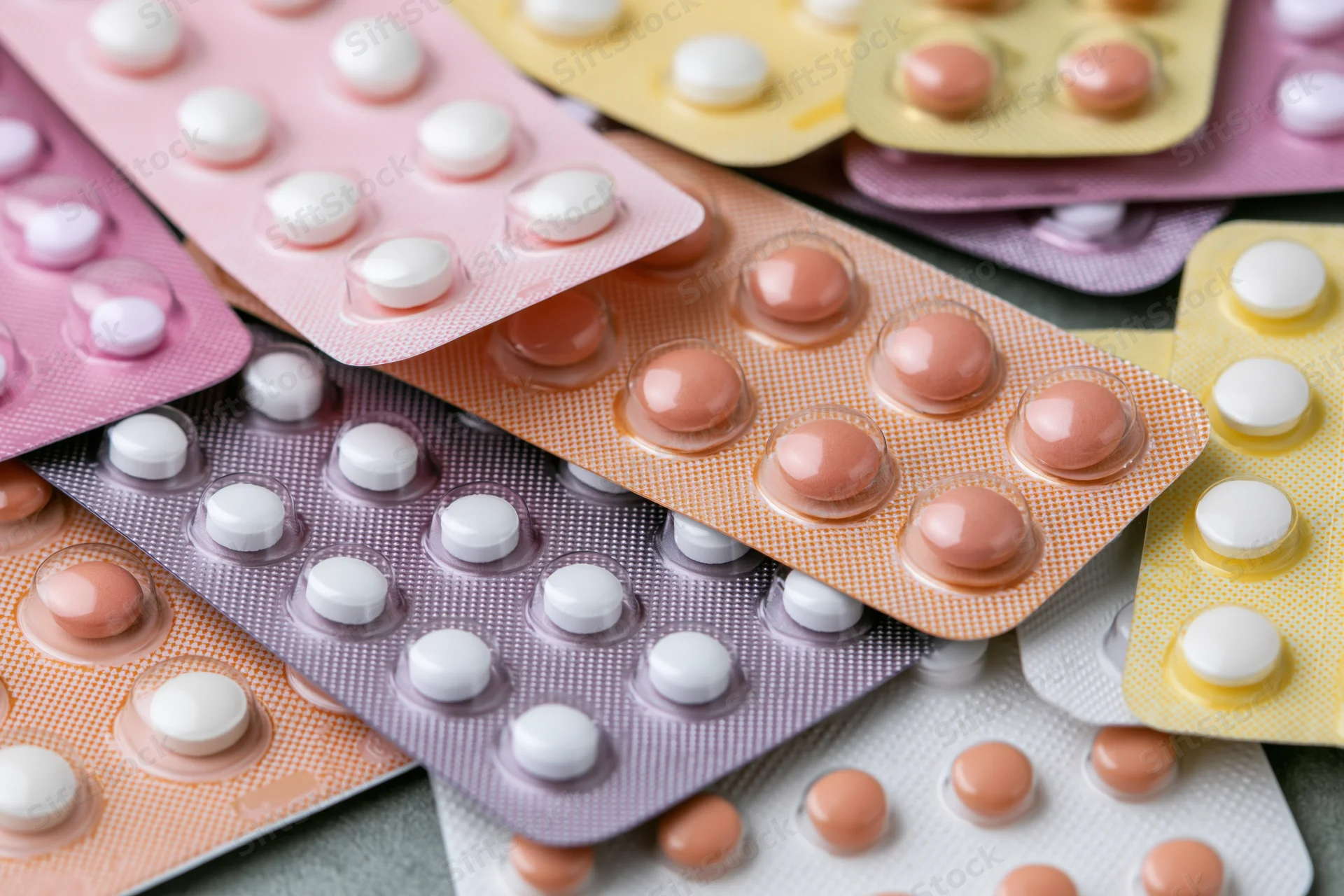 Multiple blister packs of oral contraceptive pills layered on a surface
