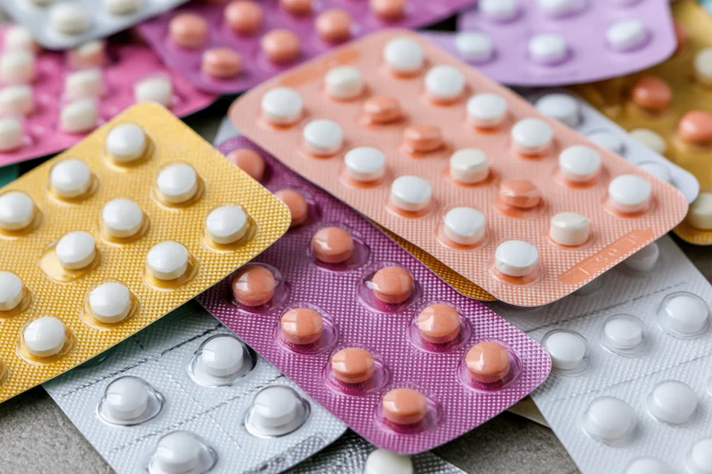 Multiple blister packs of oral contraceptive pills layered on a textured surface