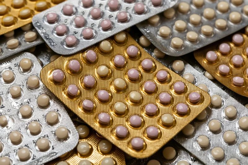 Multiple oral contraceptive pill blister packs arranged overlapping on surface