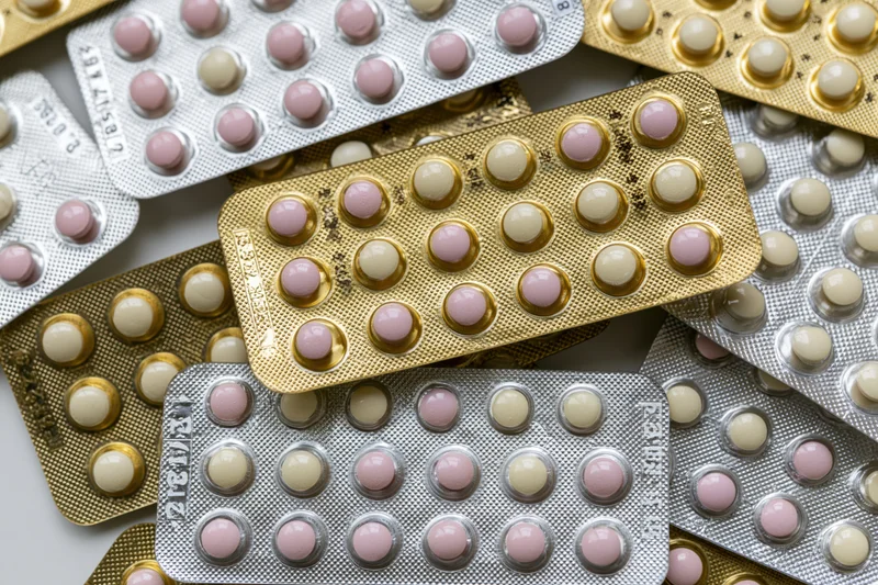 Multiple oral contraceptive pill blister packs arranged overlapping on a flat surface