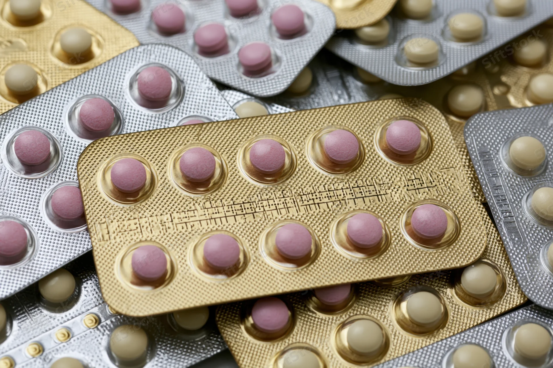 Multiple oral contraceptive pill blister packs arranged overlapping in close-up view