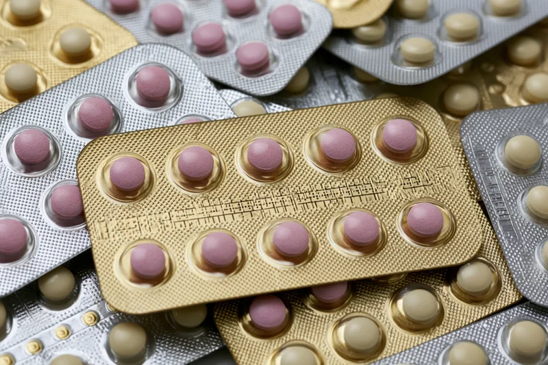 Multiple oral contraceptive pill blister packs arranged overlapping in close-up view
